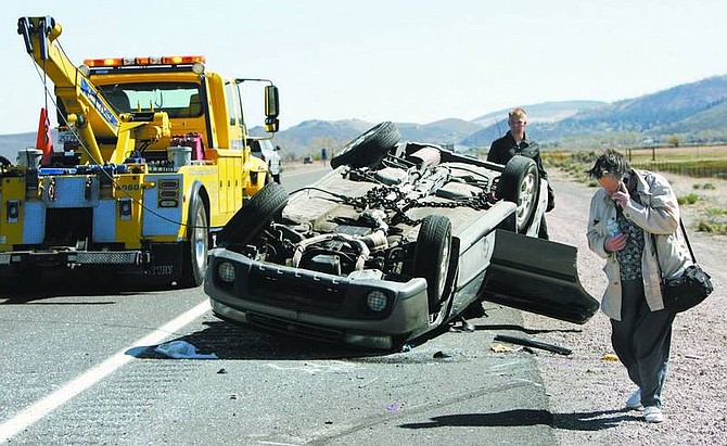 Chad Lundquist/Nevada Appeal Christine L. Jones, 54, of Silver Springs, makes a phone call while waiting to collect her belongings after a gust of wind caused her to lose control and flip her car.  Her daughter-in-law suffered a head injury and was taken from the scene in Washoe Valley by helicopter Monday.