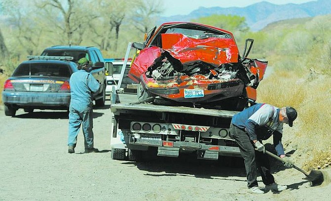 BRAD HORN/Nevada Appeal A tow truck driver gets ready to transport the red Ford Mustang that was involved in a two-car accident on Fort Churchill Road in Silver Springs on Friday morning. A 17-year-old boy was killed, and four other teens were taken to the hospital.