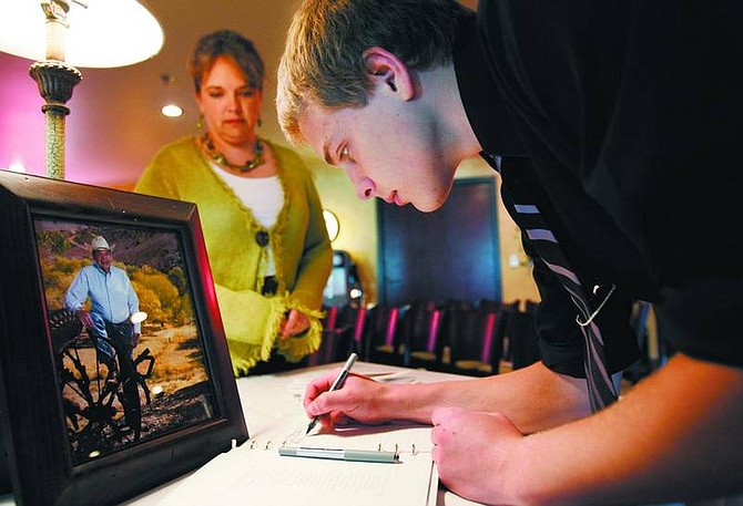 Alexander Schacht, 16, great-grandson of JohnD Winters, accompanied by his mom, Kathleen, signs a guest book at Winters&#039; memorial at Silver Oak Golf Course on Wednesday.  Chad Lundquist/ Nevada Appeal