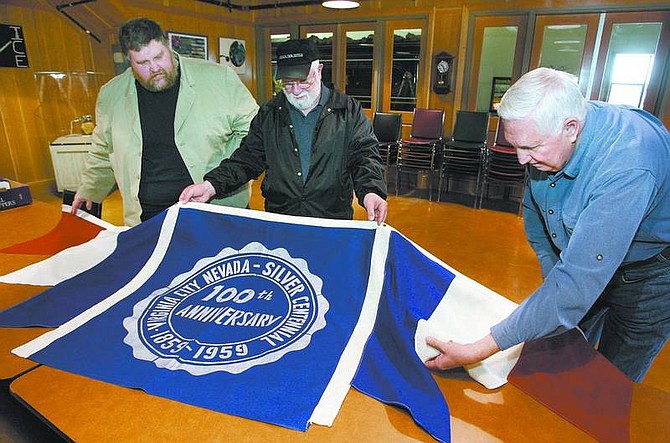 Cathleen Allison/Nevada Appeal From left, Comstock Historic District administrator Bert Bedeau, Chic DiFrancia and Doug Klawsnik look at a historic Virginia City banner Tuesday. Nearly 50 years ago the banner was swiped by Klawsnik and a friend during the 100-year celebration. The theft likely led to the banner&#039;s salvation. It&#039;s new home will be with the Comstock History Center.