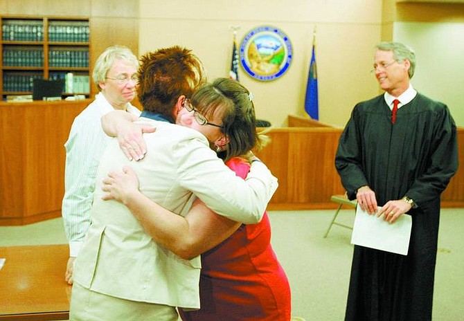 BRAD HORN/Nevada Appeal Marie Saxon hugs mental health director Lisa Treinan while Judge John Tatro looks on after Sexon graduated from the program on Wednesday. Sexon has been clean from all drugs for more than a year, after battling a 20-year drug addiction.