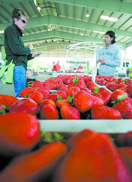 BRAD HORN/Nevada Appeal Rebecca DeLeon and Moises DeLeon, 2, of Carson City, buy strawberries at the farmers market at the Pony Express Pavilion at Mills Park on Wednesday.