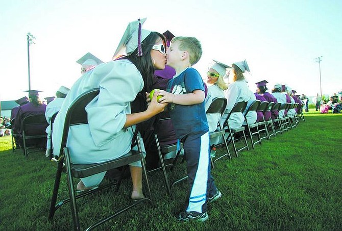 photos by BRAD HORN/Nevada Appeal Dayton senior Teryn Kukuk, 17, gives her 3-year-old brother Michael a kiss after he brought her an apple during graduation ceremonies at Dayton High School at the football field on Thursday.