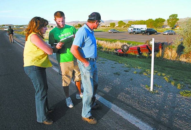 Adam Houghton, center, fills out a statement Thursday night after he helped rescue a man injured in a rollover accident on Fifth Street. The car landed in a ditch and Houghton held the man&#039;s head out of the water until he could be cut from the car. Houghton and his parents Pam and Roy were driving in front of the man when he lost control.   Cathleen Allison/Nevada Appeal