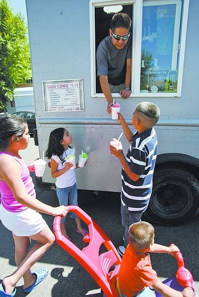 Chad Lundquist/Nevada Appeal Luis Leon hands a group of kids their snow cones on Wednesday afternoon.