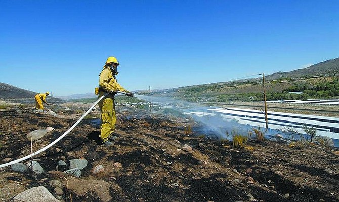 Kevin Clifford/Nevada Appeal Reno firefighters put out hotspots from the Mae Anne fire in west Reno Sunday afternoon.