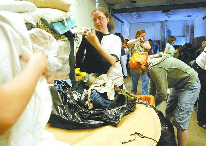 Dan Thrift/Nevada Appeal News Service Erin Bechtol, center, sorts donated clothing in the Tahoe Daily Tribune&#039;s old pressroom on Monday afternoon.