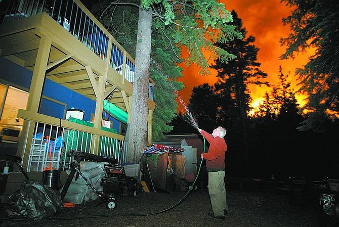 Brad Horn/Nevada Appeal Michael Lee protects his home against the Angora fire at the corner of Taylor Way and 13th Street in South Lake Tahoe at around 2:30 a.m. Monday.