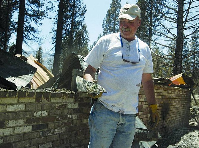 Emma Garrard/Nevada Appeal News Service John Lilygren, former Battalion Chief for South Lake Tahoe Fire Department, looks at the remains of his retirement ax in the burned rubble of his home.