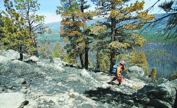 Chad Lundquist/Nevada Appeal An inmate firefighter negotiates the steep terrain while looking for hot spots along Angora ridge while doing mop-up work on the Angora fire in South Lake Tahoe.