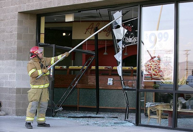 Cathleen Allison/Nevada Appeal Carson City Fire Capt. Eric Bero knocks down loose glass at Papa Murphy&#039;s, in South Carson City on Thursday night, after a woman drove into the store front nearly hitting several employees and customers.