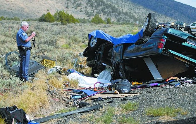 Kevin Clifford/Nevada Appeal A Nevada Highway Patrol trooper takes photos of an accident that killed three people on Highway 395 south of Gardnerville on Saturday afternoon. One other person was flown to Renown Regional Medical Center in Reno.