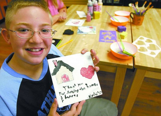 Trevor Clark/Nevada Appeal Kyle Cavner, 10, holds up a tile he painted Friday in thanks to the firefighters who battled the Angora fire in South Lake Tahoe.