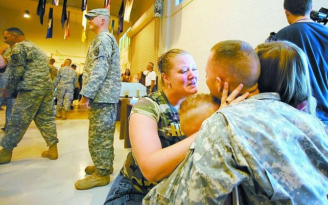 Brad Horn/Nevada Appeal Tera Lusby greets her husband Sgt. Kyland Lusby, while their children huddle around the guardsman at the Plumb Lane Armory in Reno on Saturday after the soldier from the Nevada Army Guard&#039;s 1/221st Cavalry returned from a one-year deployment in Iraq.
