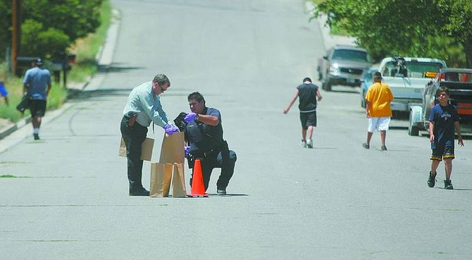 BRAD HORN/Nevada Appeal Tribal Police Chief Richard Varner, left of orange cone, and an unidentified tribal police officer investigate the scene on Oneida Street at the Carson Colony after a fight between two adult men on Wednesday. One of the men was flown to a Reno hospital.