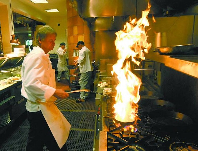Kevin Clifford/Nevada Appeal Todd Boerner, chef for the Station Grille, creates a flame while cooking Spanish shrimp in olive oil in the Grille&#039;s kitchen on Friday.