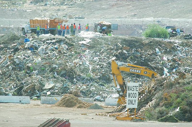 Inmates, in orange, help customers at the Carson City landfill unload trash on Thursday morning. Some victims of the Angora fire are towing their refuse to the landfill.   BRAD HORN/ Nevada Appeal