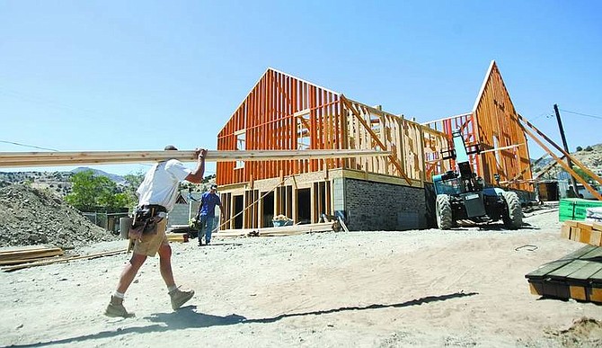 Chad Lundquist/Nevada Appeal A construction worker for Building Solutions LLC moves lumber to the new Silver City Schoolhouse. The walls of the reconstructed schoolhouse were erected on Monday, marking the first signs of the return of the building that burned down in 2004.