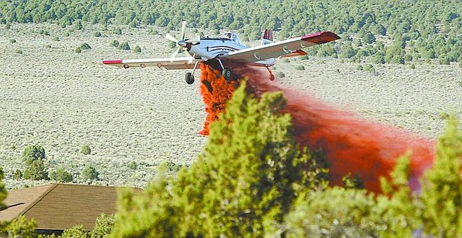 Shannon Litz/Appeal News Service A plane drops slurry on the fire in the Pine Nuts on Friday.