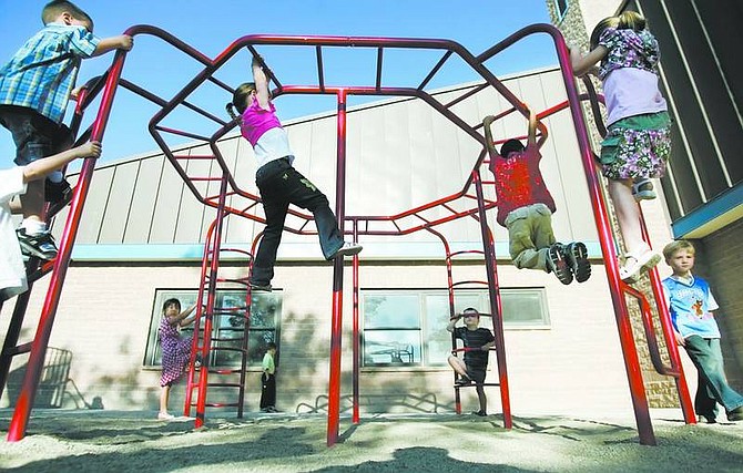 Chad Lundquist/Nevada Appeal Kindergartners swing and climb from a jungle gym while waiting for the first day of school to start Monday morning at Bordewich-Bray Elementary School.
