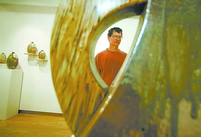 BRAD HORN/Nevada Appeal Artist Joe Winter is framed in one of his slab tea pots while installing his work for the exhibit &quot;Pyrotechniques II: An Interplay of Form, Surface and Fire&quot; on Friday.