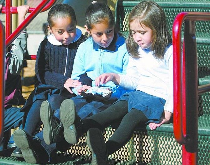 Emma Garrard/Nevada Appeal News Service Brittney Sanchez, 5, Lupita Hernandez, 5, and Cecilia Garcia, 5, eat snacks on the playground at Kings Beach Elementary School last week. Students at the school are required to wear a uniform.