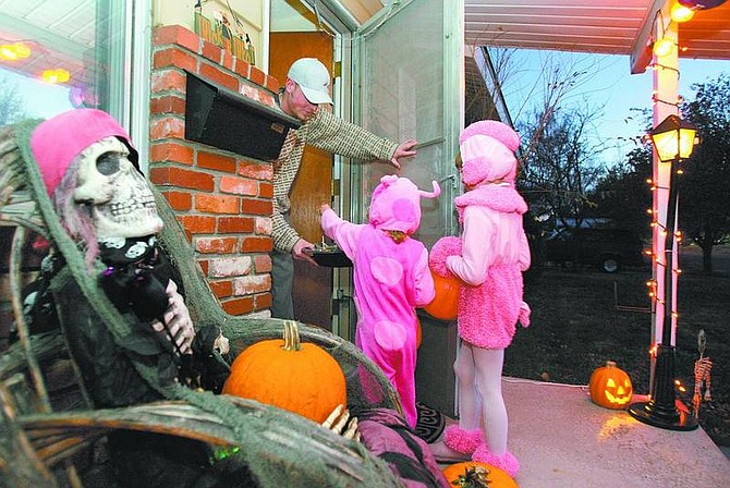 Cathleen Allison/Nevada Appeal Chris Ensminger hands out candy to Macie, 3, and Melia Fox, 6, on Wednesday night.