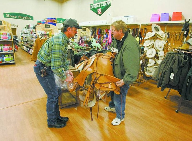 BRAD HORN/Nevada Appeal Sales representative Dale Bentien assists S and W Feed Supply owner Stan Kolbus with a saddle at his new location in Carson City on Wednesday.