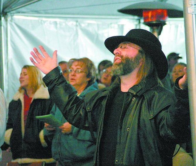 Amy Lisenbe/Nevada Appeal Preacher Tony Grasso raises his hands as he sings during the Connected Church of the Nazarene services Sunday under a tent in the parking lot near the church&#039;s building. The sanctuary was destroyed in a fire Dec. 2.