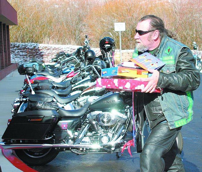 Amy Lisenbe/Nevada Appeal &quot;Awful Al,&quot; a rider in the Vagos group, carries in an armful of gifts for Eagle Valley Children&#039;s Home residents Sunday afternoon. Local riding clubs that participated in the toy drive for the home brought the residents presents, Christmas cheer and a monetary donation.