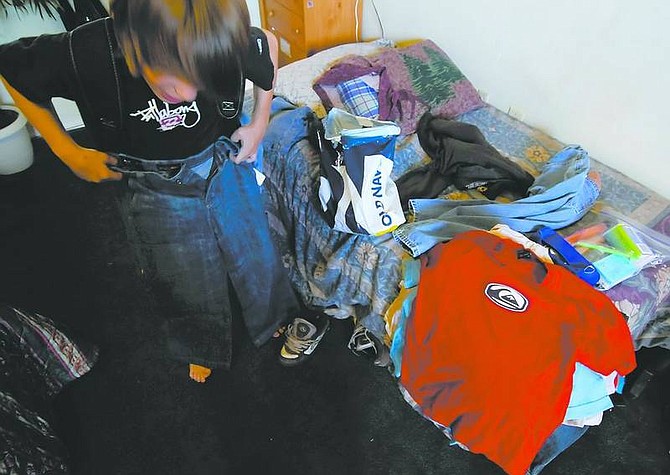 Kevin Clifford/Nevada AppealA student, who was in need of cloths that fit him and school supplies, shows off his new cloths that came with a new backpack donated by the Well of Worship church of Mound House the day before school on Sunday.