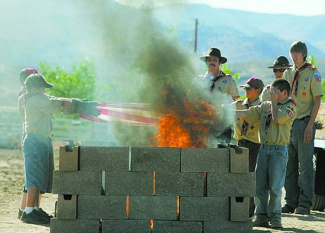 BRAD HORN/Nevada AppealLife Scout Julian Ballatore-South, back right, assistant Scoutmaster John Alexander, in hat and sunglasses, and Dan South, Scoutmaster, behind fire, watch Boy Scouts burn an American Flag as part of Ballatore-South&#039;s Eagle Scout project during a flag retirement ceremony he organized at Dayton Valley Events Center Wednesday.