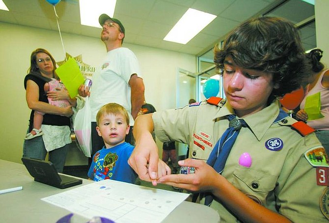 BRAD HORN/Nevada Appeal Dion Copoulos, 14, a Life Scout in Troop 341, fingerprints Johnathan Ammerman, 4, while his parents John and Julie watch in the background at the Carson City Sheriff&#039;s office during an open house Saturday.