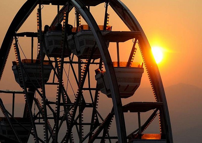 Kevin Clifford/Nevada AppealThe sun sets behind the ferris wheel at the Reno Rodeo on Monday. Smoke from the California fires has caused the sun to appear bright orange and red during sunrises and sunsets.