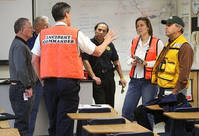 Cathleen Allison/Nevada AppealCarson City Fire Departement Battalion Chief Dan Shirey, center, talks with city, school and EPA officials Wednesday afternoon following a mercury spill at Carson High School. 22 students and a teacher were quarentined for several hours.