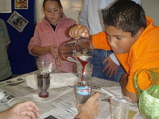 Teri Spraggins/Special to the Nevada Appeal Mark Twain Elementary School student Christian Senda pours a red solution into one soil soaker to compare water drainage with the hydrogels, with student Cindy Cardenas in the background. Cooperative Extension instructor Jim Barcellos supervised the project as part of 4-H National Science Day.