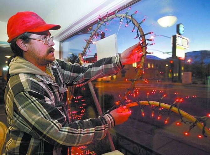 Amy Lisenbe/Nevada Appeal &quot;Willow Bill&quot; Goulardt adjusts lights spiraled around a heart made of willow branches as he installs it in the window at a treasure hunt location in Carson City Monday evening. The hearts include a photo of a prominent person in Carson&#039;s history and help commemorate the city&#039;s sesquicentennial.
