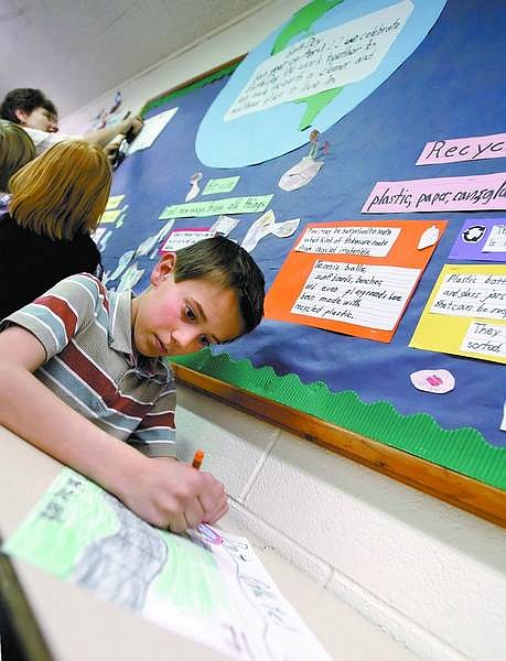 Amy Lisenbe/Nevada Appeal Bryce Bauer makes finishing touches to his Earth Day poster Friday as his teacher, Kim Hickenbottom, and a group of his second-grade classmates attach their Earth Day posters to a bulletin board at Fritsch Elementary School for Earth Day on Tuesday. Bauer&#039;s poster, along with many others, focused on anti-pollution.