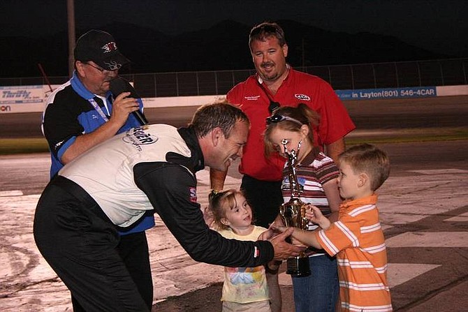 Rhonda Costa-Landers/NevadaAppealTroy Regier, left, driver of the No. 98 S&amp;S Motorsports supermodified racecar, accepts his main event trophy from the Rocky Mountain Raceways trophy kids Saturday night.