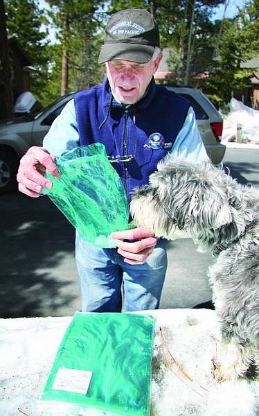 Paul Guttman and dog Smudge examine a snow-filled flushable dog poop bag, which breaks down in minutes with the addition of water.  The corn starch-based bag biodegrades quickly in nature, said Guttman, who is working on the project with Madonna Dunbar, IVGID&#039;s resource conservationist.   Jen Schmidt/ Nevada Appeal News Service