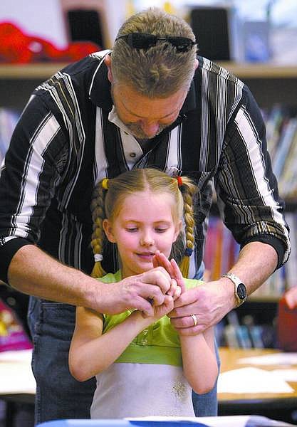 Amy Lisenbe/Nevada Appeal Bruce Magner, an instructor assistant who helps out with the Fremont Elementary Sign Language Club, shows Briana Huff, a second-grader, the correct way to sign months of the year Monday morning during a club meeting at recess.