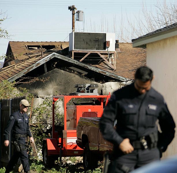 Los Angeles police officers stand near a burned home Friday, Feb. 8, 2008, where a gunman killed four people including a SWAT office in Los Angeles. Los Angeles County coroner&#039;s officials said no additional bodies were found inside the house where the four people and the gunman, were shot to death the previous day. (AP Photo/Nick Ut)