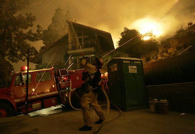 AP Photo/Dan SteinbergFirefighters protect homes from a wind driven brush fire in the foothills of Sierra Madre, Calif. on Monday, April 28, 2008. A flare up early Monday morning caused the fire to push towards and threaten numerous homes in the town of Sierra Madre.