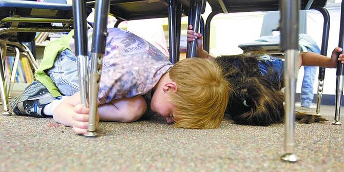 Amy Lisenbe/Nevada Appeal Mark Twain Elementary School second-graders Henry Enge, front, and Jasmine Peralta, back, duck and cover as part of an earthquake preparedness drill Monday morning.