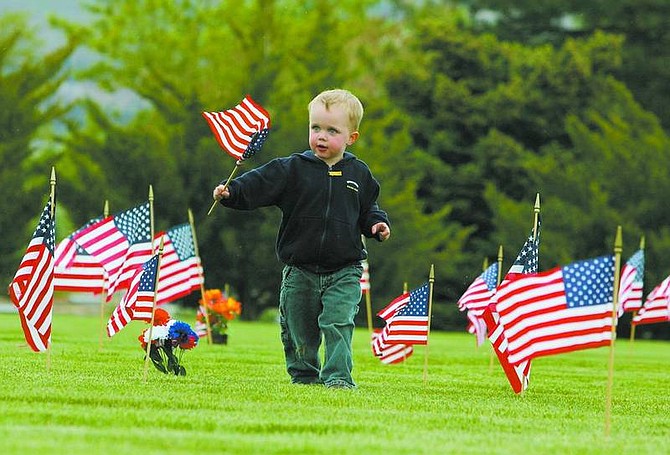 BRAD HORN/Nevada Appeal Nolan Pedersen, 2, of Carson City, helps place flags on veterans&#039; graves at Lone Mountain Cemetery on Friday in preparation for Monday&#039;s Memorial Day ceremony.