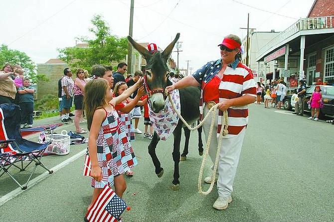 BRAD HORN/Nevada Appeal Morgan Crofoot, 7, from back, Austin Crofoot, 8, and Morgan&#039;s twin Taylor, of Reno, are introduced to a donkey adopted by the Wild Ass Women at the parade on Friday.