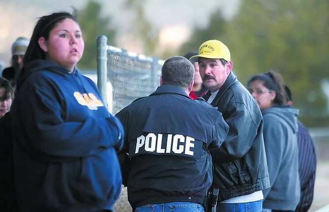 Amy Lisenbe/Nevada Appeal Tribal Police Chief Richard Varner, police jacket, advises Vernon Markussen, right, and other tribe members gathered at the Carson Indian Colony of the current situation with a tribe member on Oneida Street who allegedly fired a shotgun Sunday afternoon. Residents of homes near the scene were evacuated to the colony&#039;s center as a safety precaution.  Check www.nevadaappeal.com today for story updates.