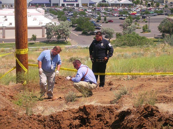 Investigators from the Carson City Sheriff&#039;s Department and a officer with the Washoe Tribal Police examine human bones found today buried on the southwest side of C Hill.