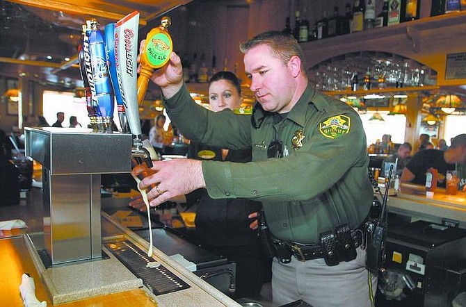 Cathleen Allison/Nevada AppealApplebees bartender Kelli Anderson watches Carson City Sheriff&#039;s Detective Dave Legros pour a beer Thursday during the Tip-A-Cop fundraiser at Applebees. Local deputies waited tables and served food and drinks during the annual event to benefit Special Olympics Nevada.