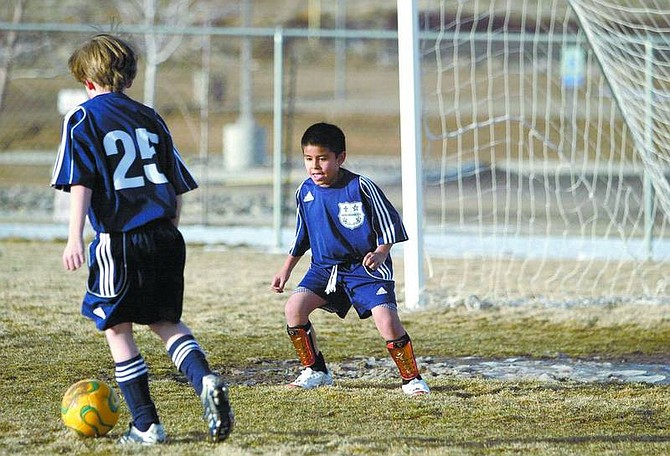 Amy Lisenbe/Nevada Appeal Bebop Martinez, 8, center, keeps his eye on the soccer ball as Nicholas Bowler, 9, left, gets ready to attempt a goal Monday afternoon at James Lee Memorial Park. The boys and fellow members of the Sierra Nevada Soccer Club will soon have a new field to play on, with about $13,000 dedicated on Monday toward rebuilding the complex where they play.